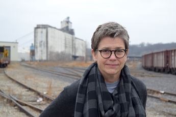 woman in front of a grain silo and train tracks