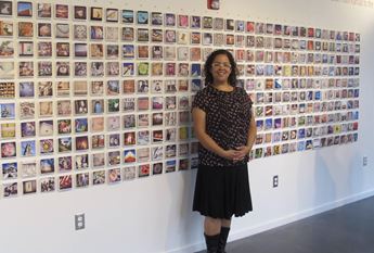 Ann Dean standing in front of exhibition of photographs