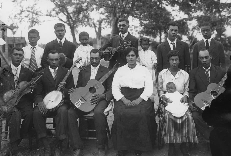 A group of African American musicians post together with their instruments, black and white.