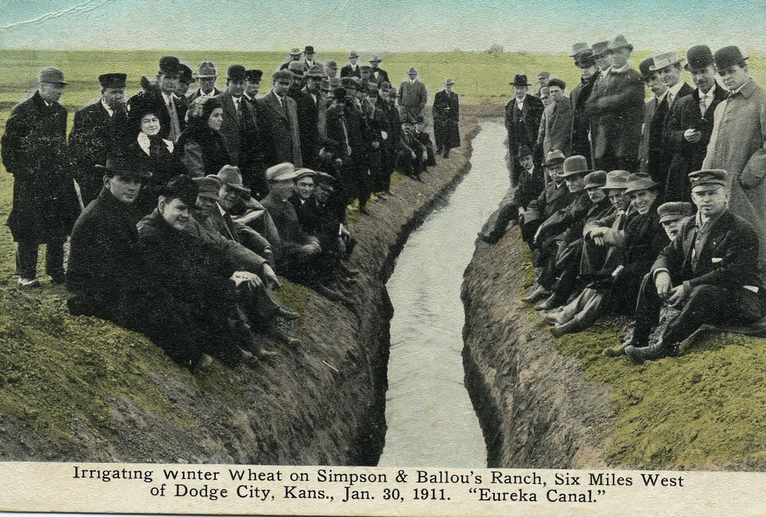 Townspeople of Dodge City stand on both sides of the Soule Canal, which has water in it - a rare site, 1911.