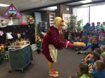 Woman in hen costume speaking to group of children