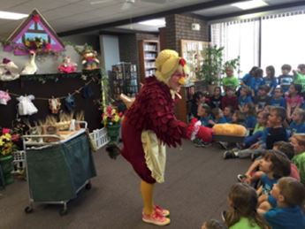 Woman in hen costume speaking to group of children 