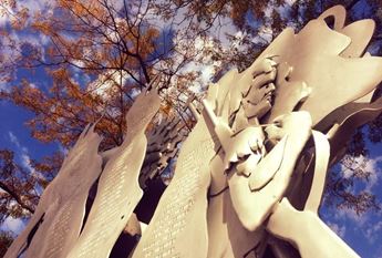 Kansas Holocaust Memorial photographed from a low angle with fall leaves and the sky above.