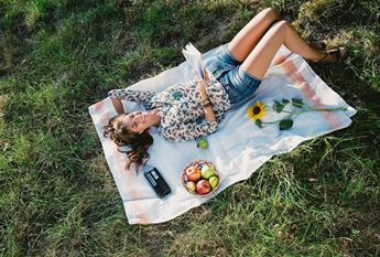 woman lying on blanket reading