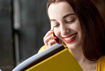 Girl reading book and talking on the phone