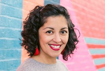 Poet Aimee Nezhukumatathil against a colorful brick background