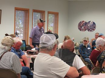 Man standing up and speaking to a group of seated people