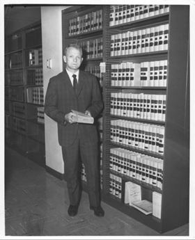 man standing in front of book shelf