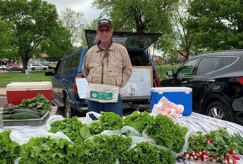 Man standing in front of produce at the Iola Farmers' Market. Photo by Robin Schallie.