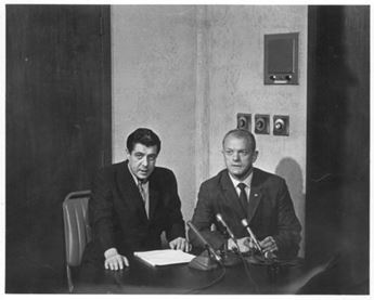 Two men sitting in front of microphones