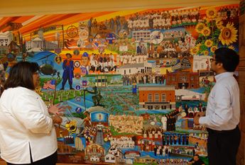 Man and woman talking in front of mural depicting Mexican American history in Topeka