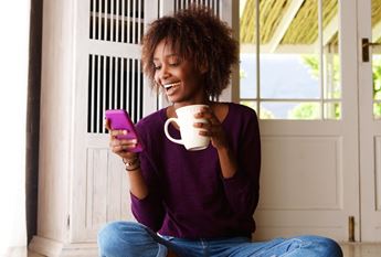 woman looking at phone and drinking coffee
