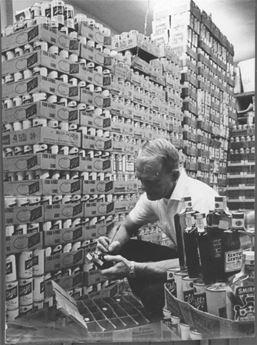 man next to boxes of beer cans