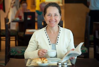 Woman drinking coffee and reading book