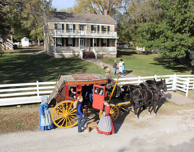 historic house with stagecoach and horses in front of it